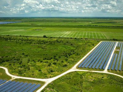 Aerial view of sustainable electrical power plant between agricultural farmlands with photovoltaic panels for producing clean electric energy. Concept of renewable electricity with zero emission.